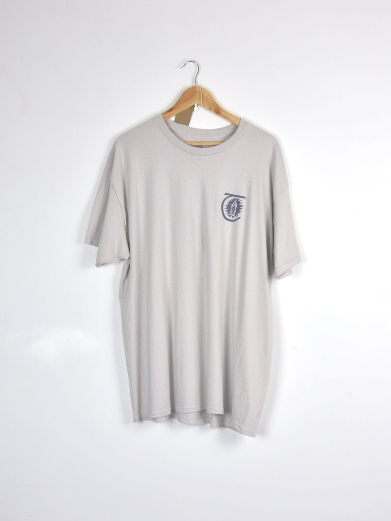 Light gray t-shirt with a small circular logo hanging on a wooden hanger.