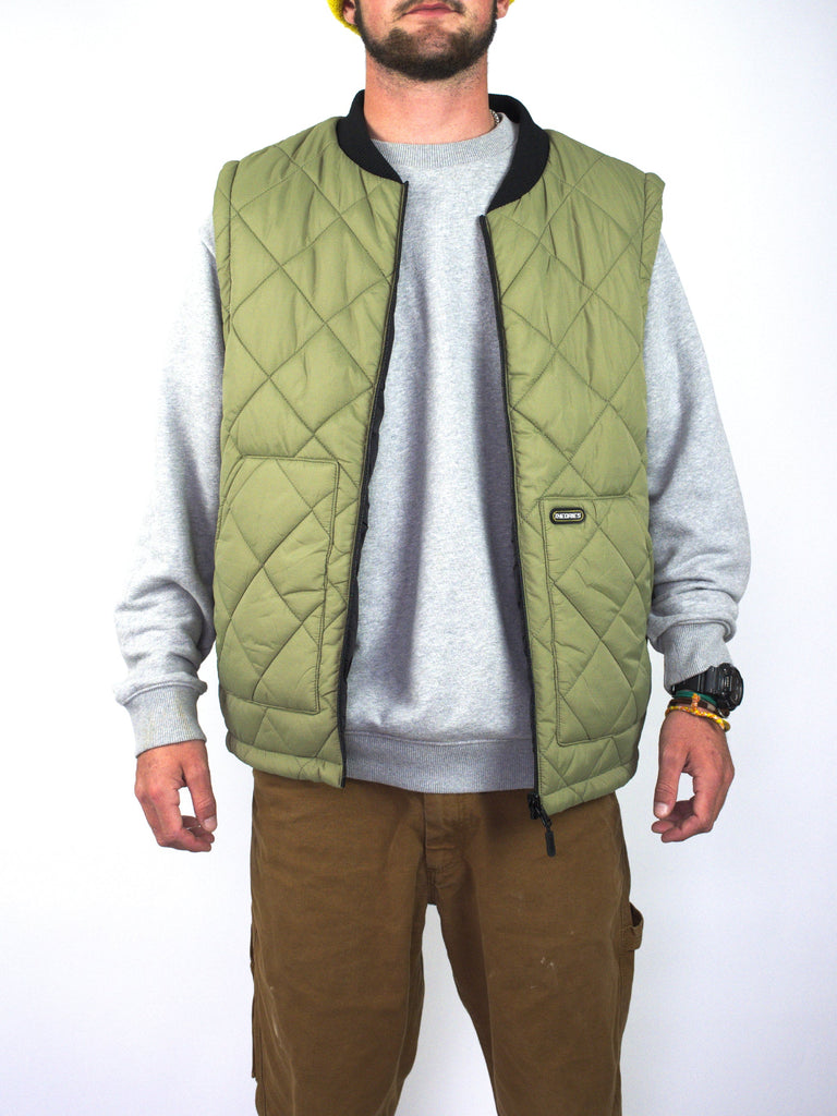 Olive green quilted vest with black trim worn over a gray sweatshirt.