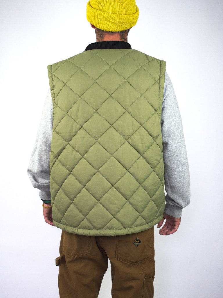 Olive green quilted vest worn over a grey sweatshirt.