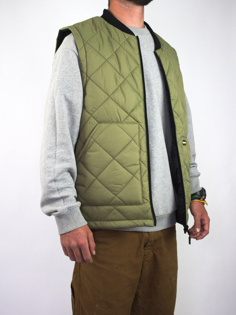 Olive green quilted vest worn over a grey sweatshirt.