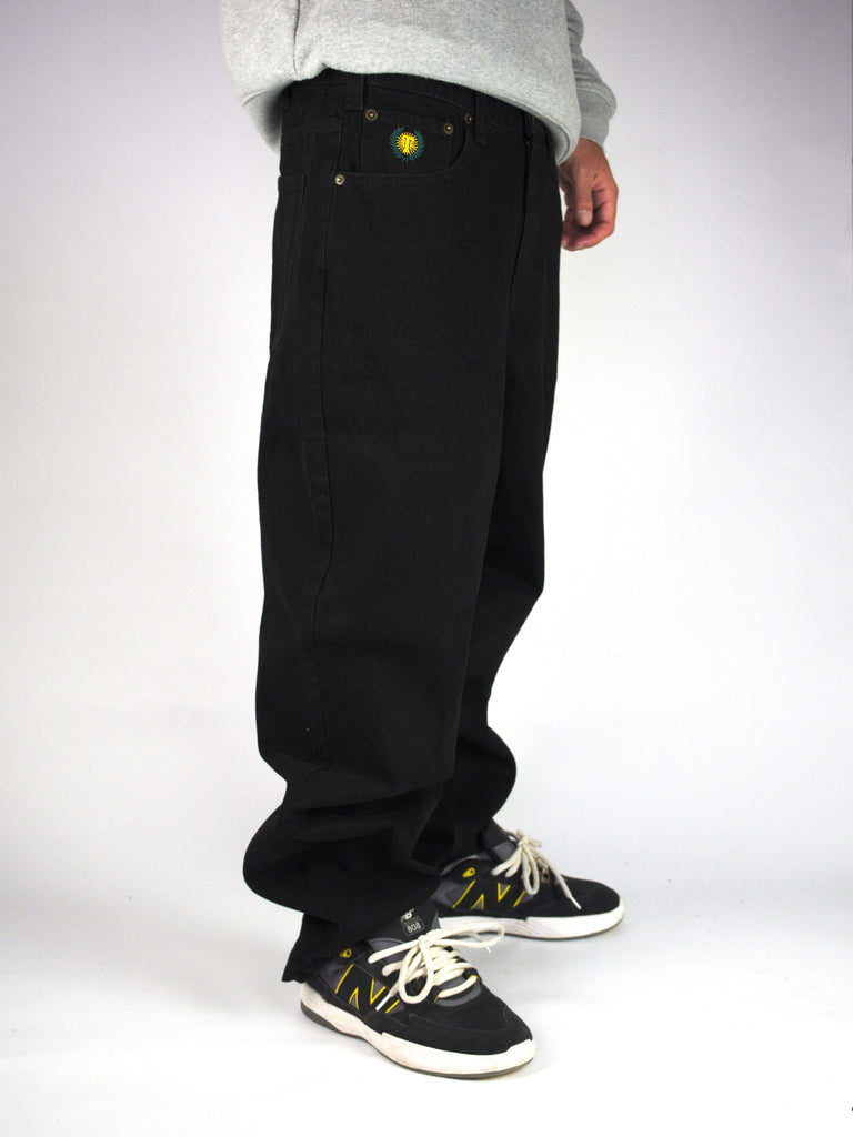 Pair of loose-fitting black jeans worn with black and white sneakers.