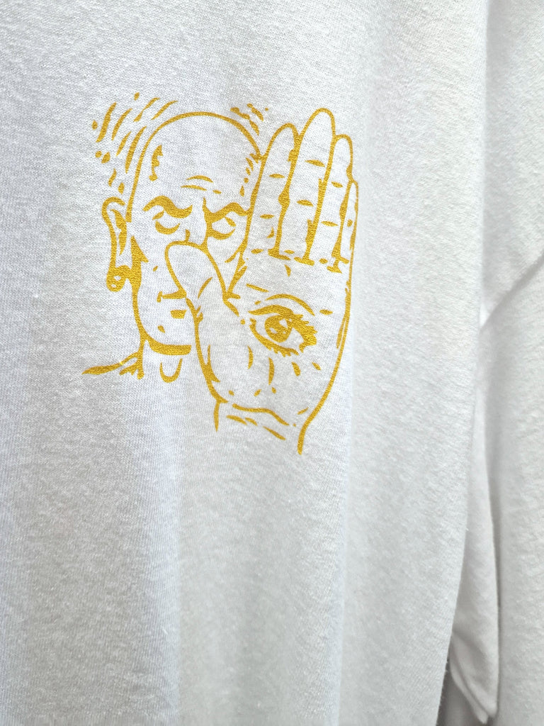 Gold line drawing of a face and hand with an eye in the palm on white fabric.