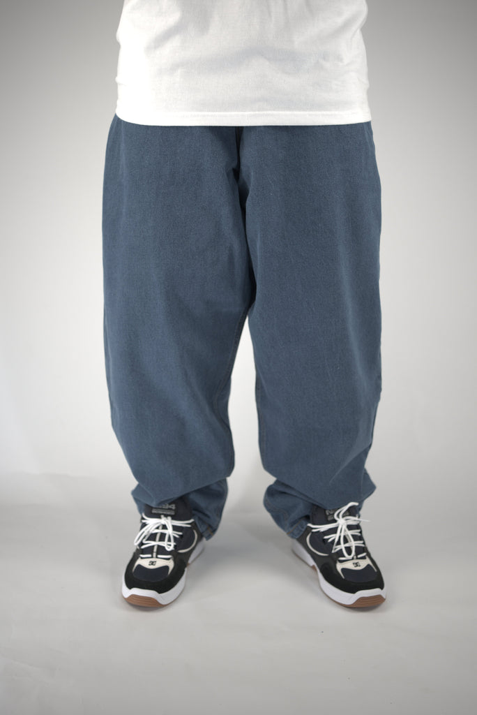 Baggy blue sweatpants styled with black and white sneakers from Three Sixty Clothing