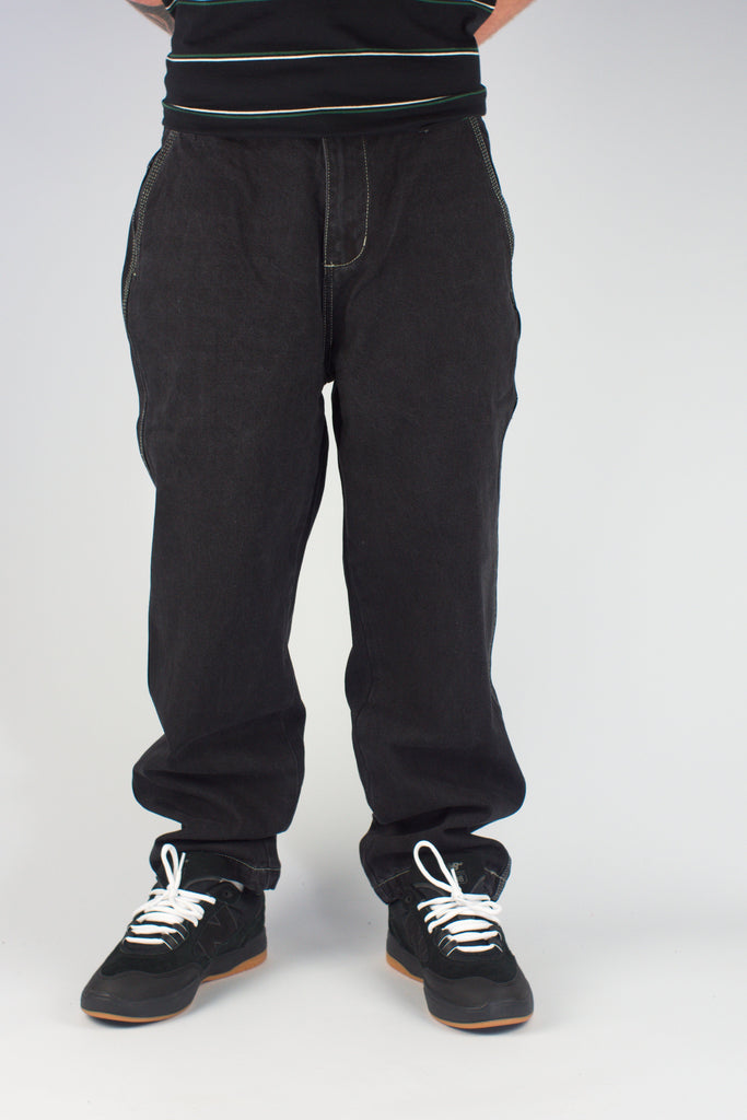 Black sweatpants with elastic waistband over black sneakers featuring white laces from Gene’s Jeans