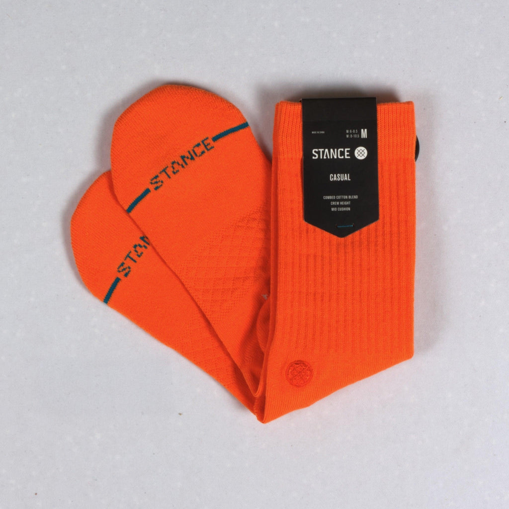 Bright orange socks with ’STANCE’ branding arranged in a heart shape.